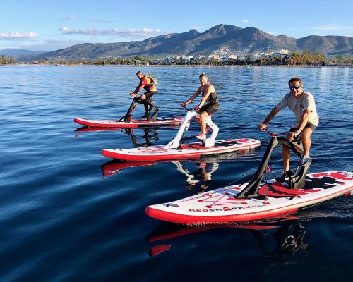 Deux waterbikes modèle fitness sur les cotés et un waterbike modèle enjoy au milieu, les trois personnes dessus sont en train de se détendre et profitent des beaux paysages des montagnes.