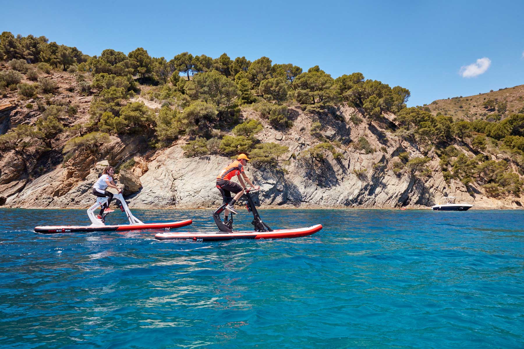 Un waterbike enjoy et un waterbike fitness sur l'eau montrant un sportif sur le waterbike fitness et une femme sur le waterbike enjoy qui profitent d'une expérience complète et unique de loisirs aquatiques.